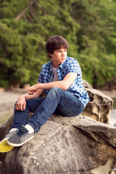 坐在岩石上的少年。图片下载