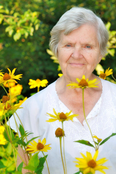 老女人在满是鲜花的花园里。图片下载