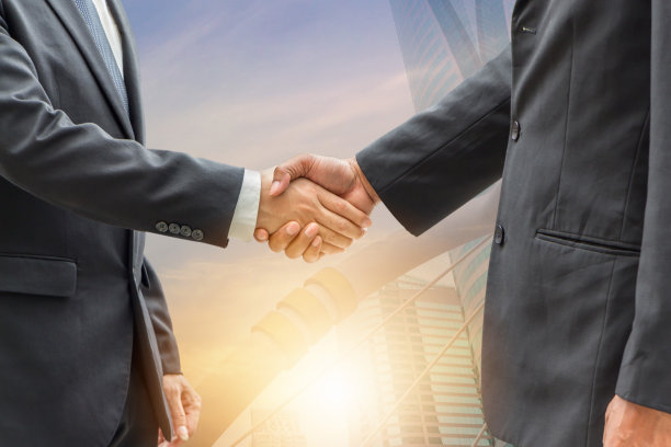 成功和幸福团队概念商人握手，双曝光照片的城市景观在日出的背景。图片下载