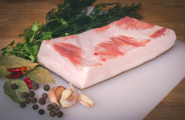 新鲜的生猪油准备好了腌在木砧板上，香料和香草。图片下载