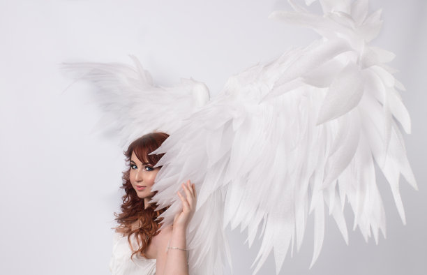 模特与开放的天使翅膀在白色的背景图片下载