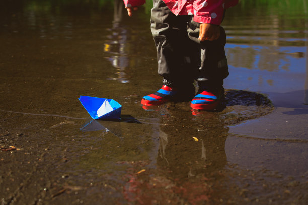 小女孩在水坑里玩纸船图片下载
