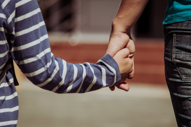 母亲手牵着背着背包的小儿子素材图片