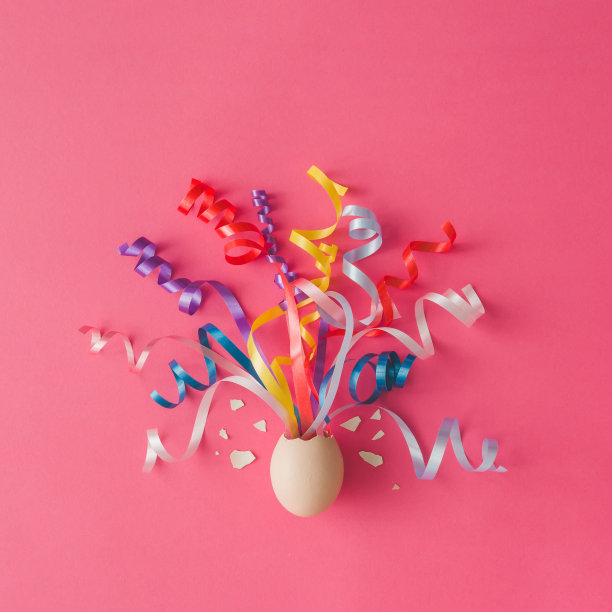 粉红色背景上带派对彩带的鸡蛋。复活节的概念。平的。素材图片