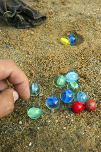 男孩的手在街上玩弹珠的特写图像图片下载