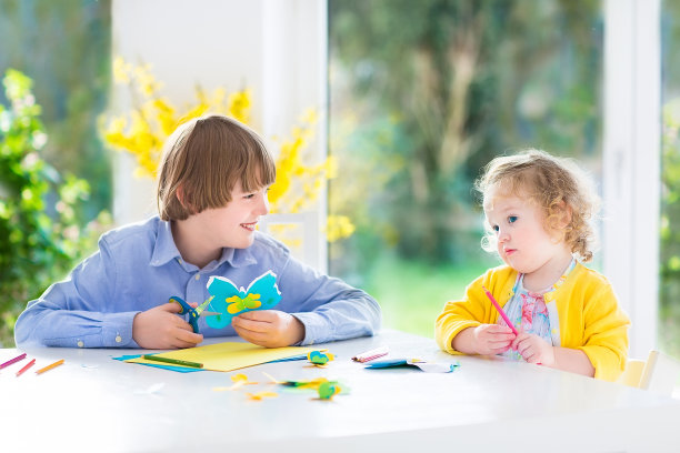 两个孩子在花园观景窗旁剪彩纸蝴蝶图片下载