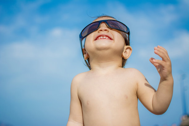 小孩戴着太阳镜抬头看太阳图片下载