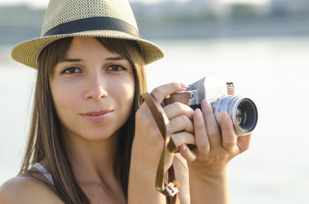 微笑的年轻女子在海滩拍照图片下载