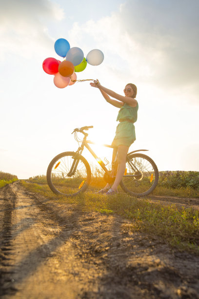年轻的女孩穿着性感的衣服，戴着太阳镜骑自行车飞行图片下载