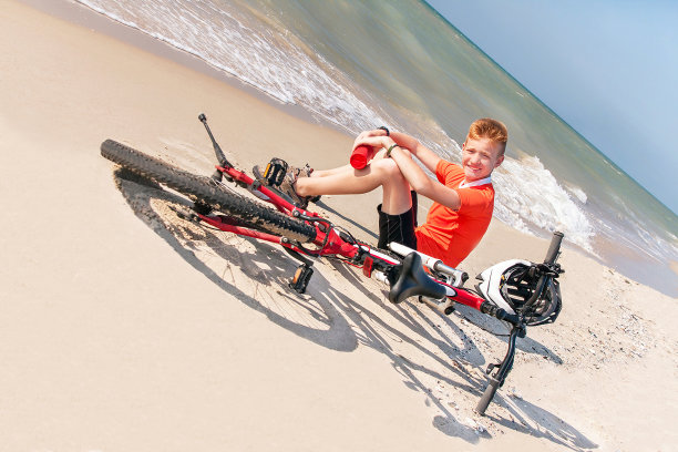 少年骑着自行车在大海的背景上。图片下载