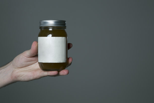 灰色背景下拿着罐子的女人的一只不规则的手图片下载