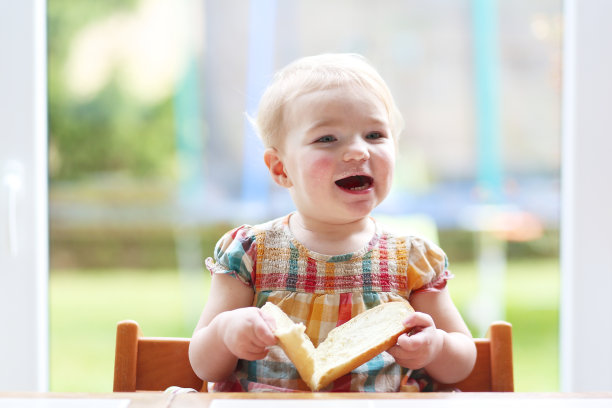 可爱的金发小女孩在吃黄油面包图片下载