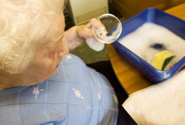 老年妇女在洗一个低水平。图片下载