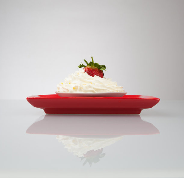 鲜奶油和草莓放在红色盘子里图片下载