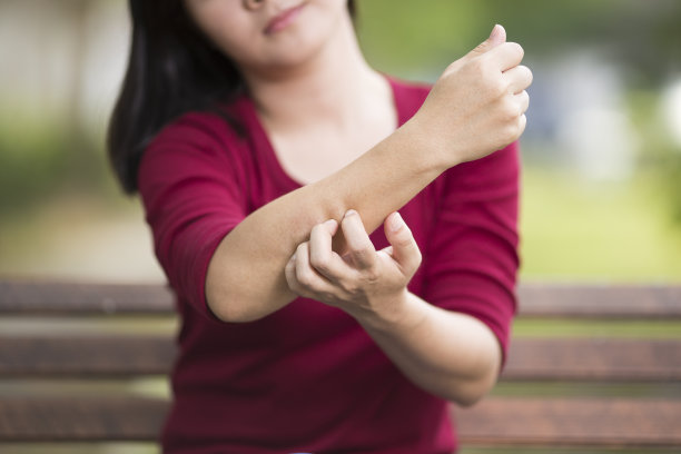 坐在公园长椅上的女人在挠手臂素材图片