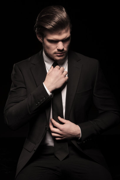 优雅的商人在打领带时，低着头图片下载