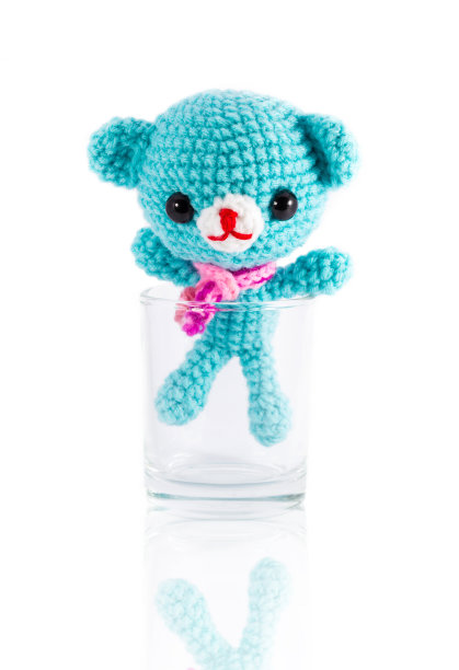 手工编织的蓝色熊娃娃在伏特加玻璃图片下载