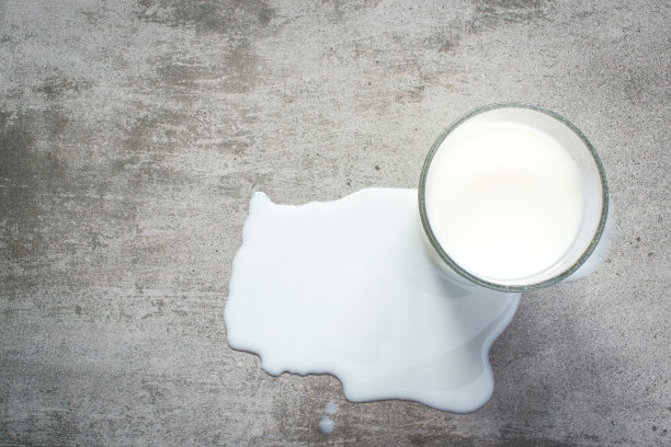 牛奶洒了，还有一杯牛奶倒在水泥桌上图片下载