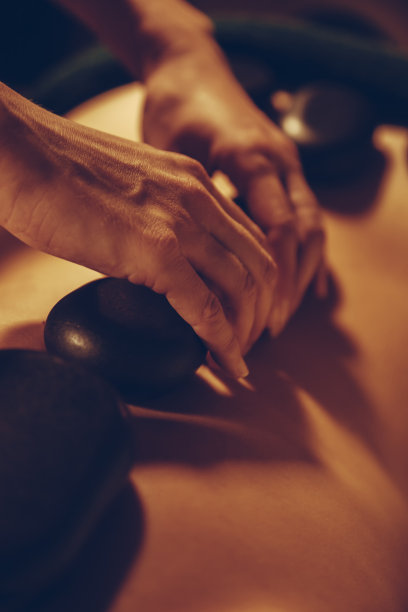 按摩师把滚烫的石头放在一个女人的背上图片下载