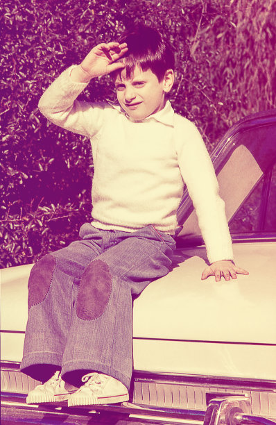 一个小孩坐在一辆白色汽车上的复古照片图片下载