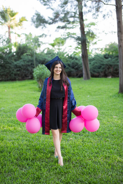 年轻漂亮的毕业女孩带着气球在野外图片下载