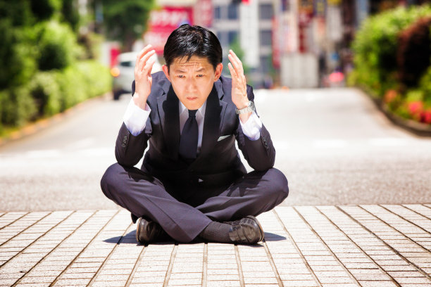 悲伤困惑的日本商人坐在人行道上图片下载