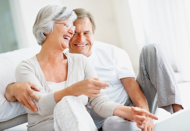 一对兴奋的退休夫妇在家里使用笔记本电脑图片下载