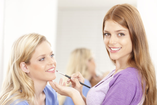 化妆师给年轻女性涂口红。图片下载