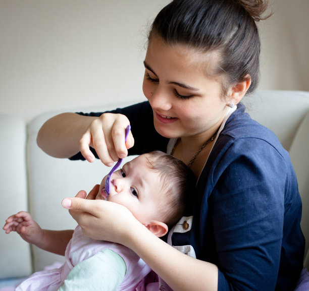 一个十几岁的女孩正在喂她的小妹妹图片下载