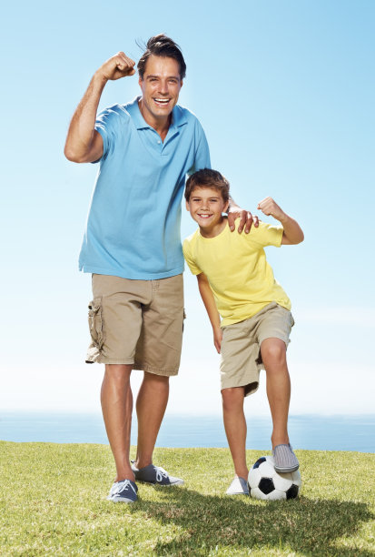 兴奋的爸爸和儿子拿着足球站在外面图片下载