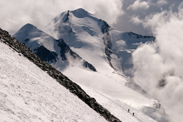 远处的登山者攀登陡峭的山坡图片下载