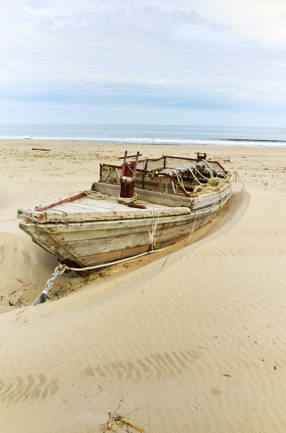 海滩上孤独的旧木船景色图片下载