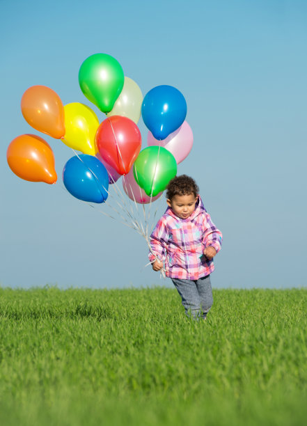 蹒跚学步的女孩在春天的田野上慢跑。图片下载
