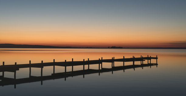 黄昏时分，湖面上桔黄色的码头剪影图片下载
