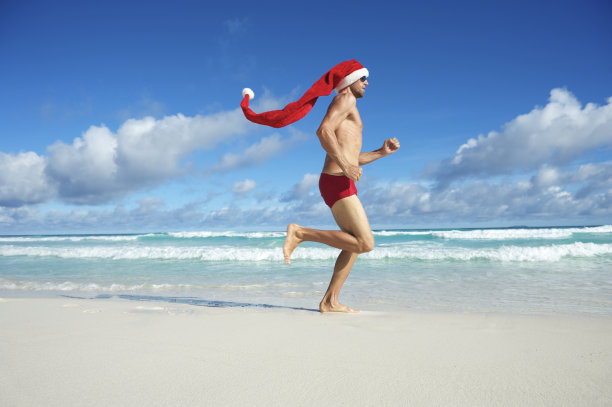 超长圣诞老人帽人跑过热带海滩图片下载