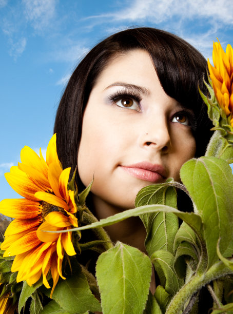 美丽的年轻女子从向日葵向上看图片下载