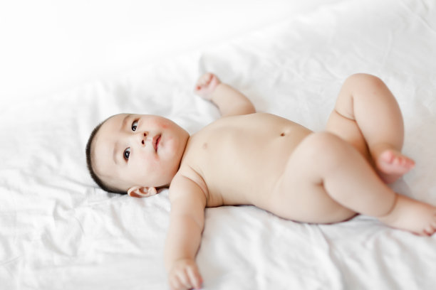 赤裸的可爱的小男孩躺在白色的床上图片下载