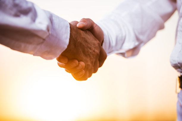 商人在日落时分握手的特写。图片下载