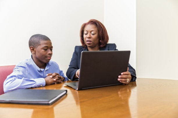 学校老师和她的学生在笔记本电脑上评论报告图片下载