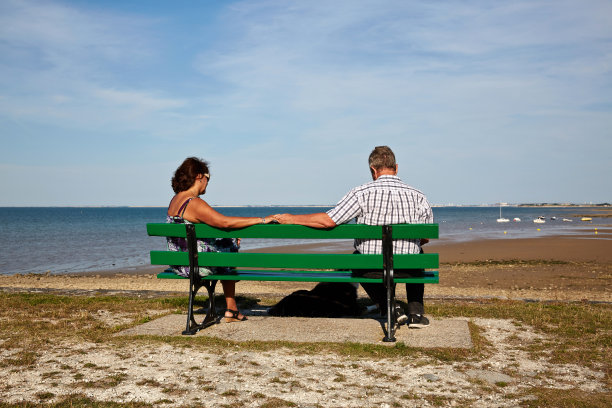 一对老年夫妇在海边的沙滩长椅上图片下载