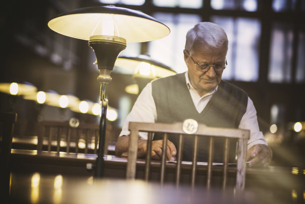 一位老人在老式图书馆的阅览室里看书图片下载