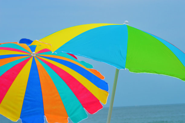 两把彩色雨伞，映衬着湛蓝的天空和大海图片下载