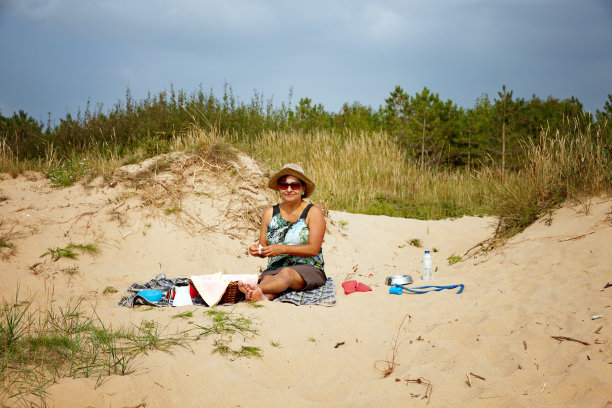 成熟的西班牙女人坐在沙丘上野餐图片下载