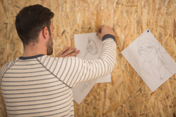 男人在墙上挂铅笔画图片下载