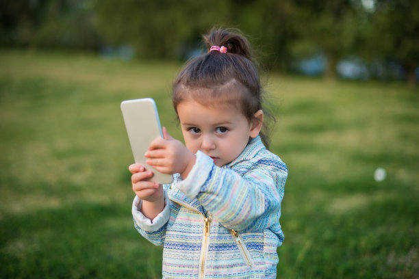 可爱的蹒跚学步的女孩使用智能手机图片下载