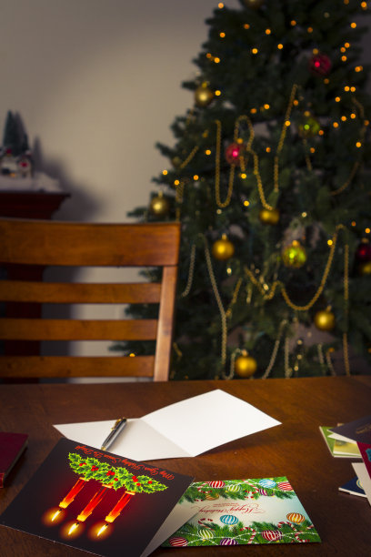 桌子上的圣诞卡，以圣诞树为背景图片下载