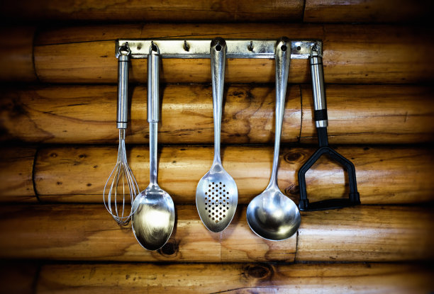 混合不锈钢厨房工具挂在小木屋的墙上图片下载
