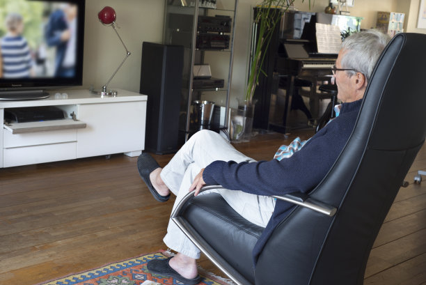老人坐在舒适的椅子上看电视图片下载