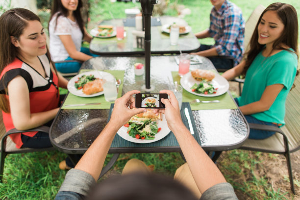 朋友们坐在桌子旁，有人在拍食物图片下载