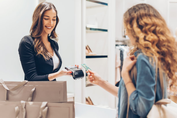 年轻女人在时装店里递出她的信用卡素材图片